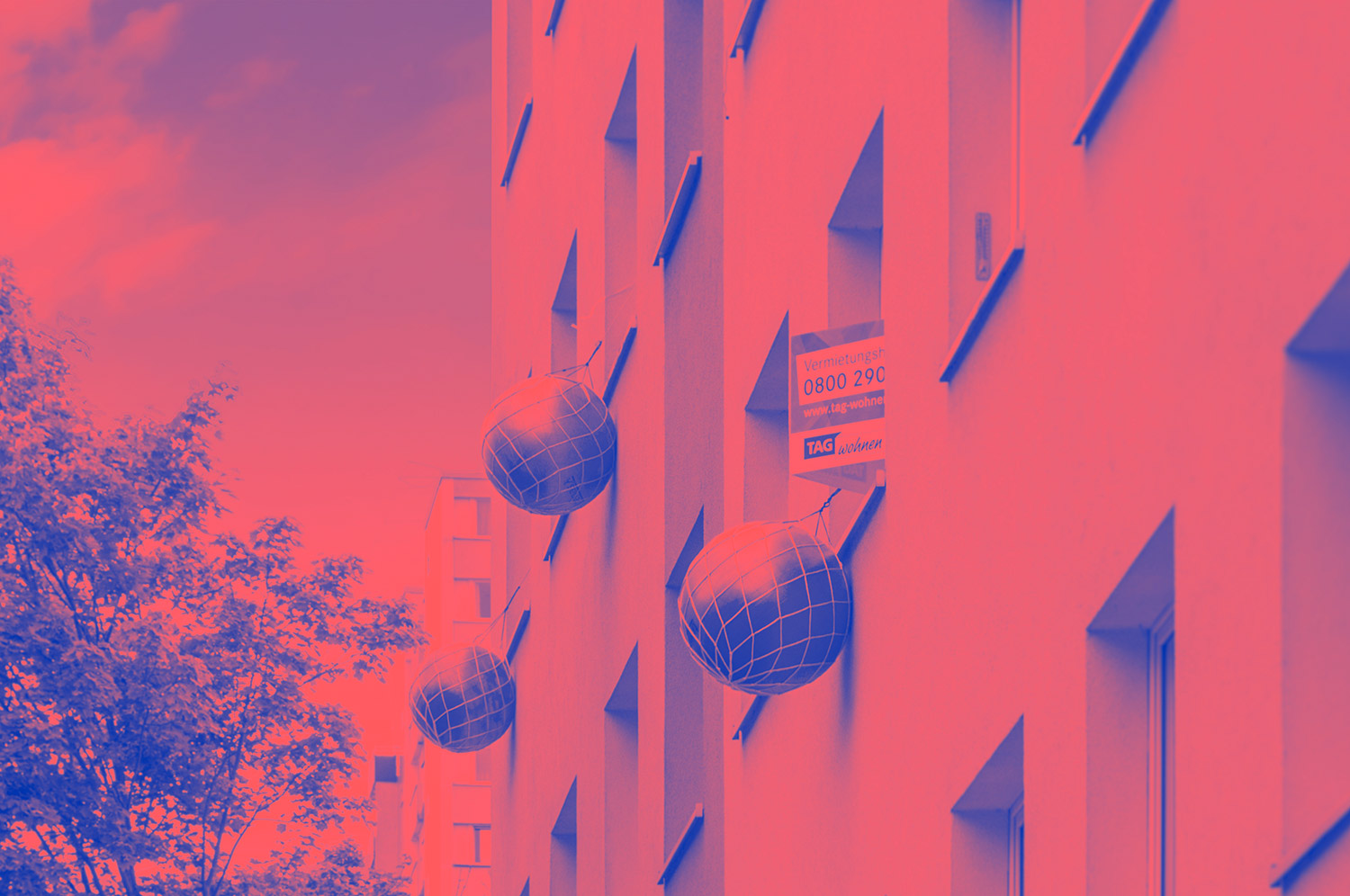 Fassade eines Wohngebäudes mit aufgehängten großen Kugeldekorationen und einem Vermietungsschild der TAG Wohnen.