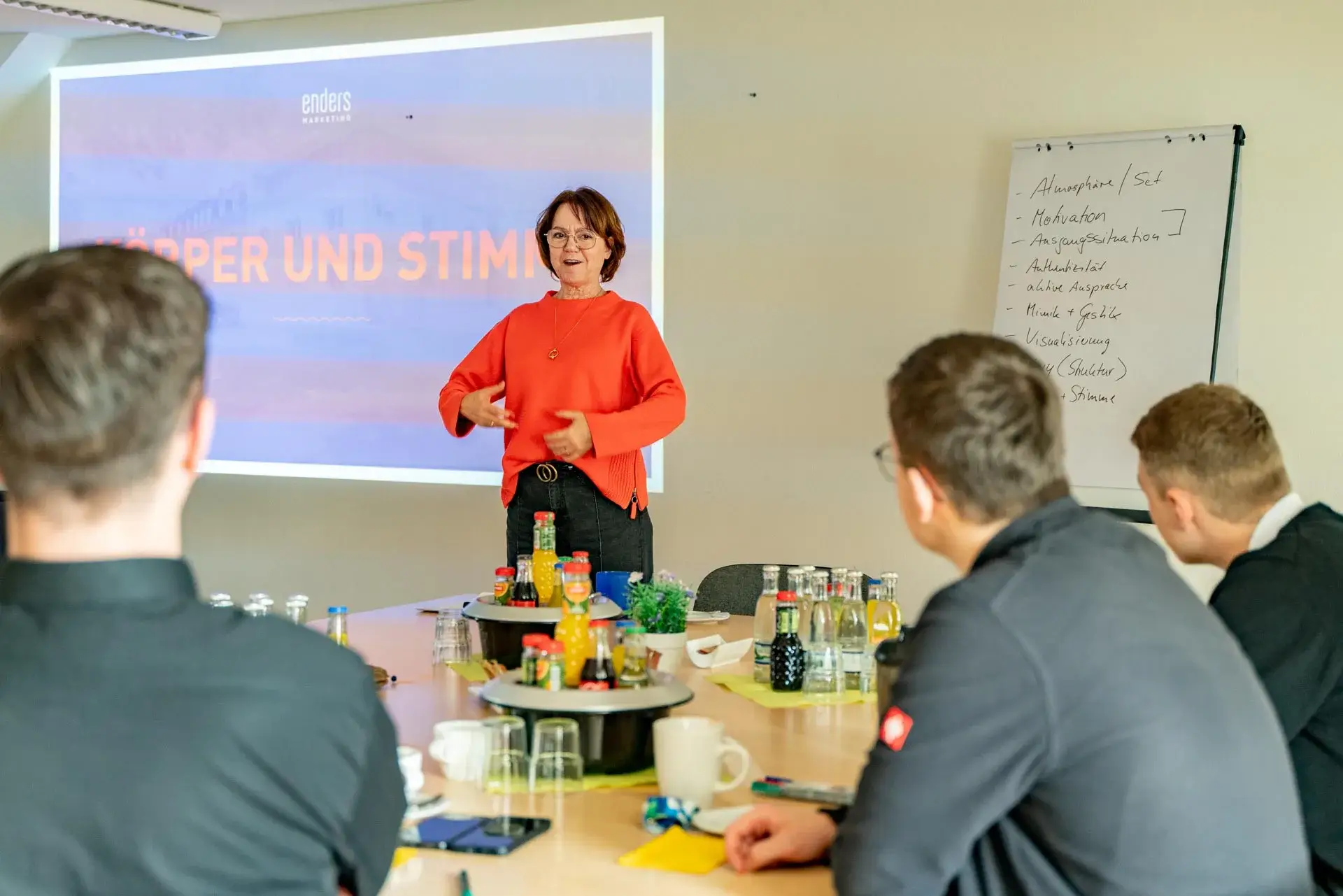 Iris Palme präsentiert vor einer Gruppe junger Menschen ein Seminar zum Thema Körpersprache und Stimme.