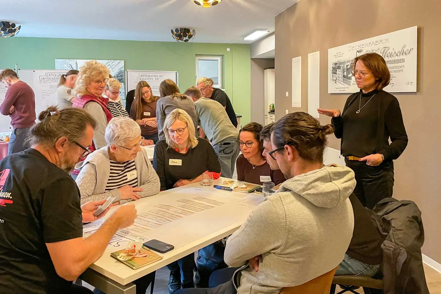 Mehrere Personen arbeiten gemeinsam an einem Tisch während eines Workshops und besprechen Notizen.