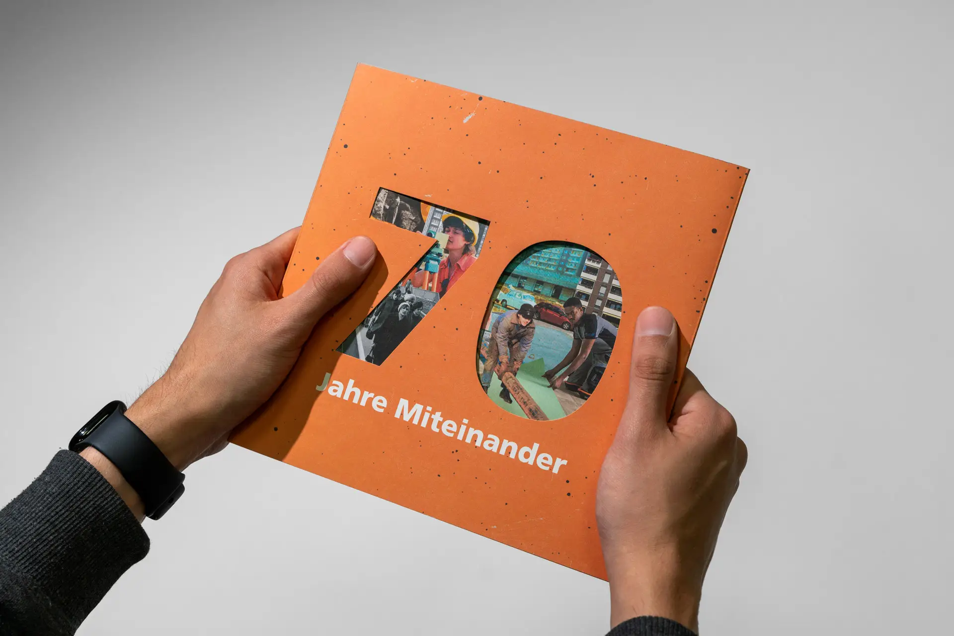 Zwei Hände halten die WBG Kontakt Chronik mit Hülle 